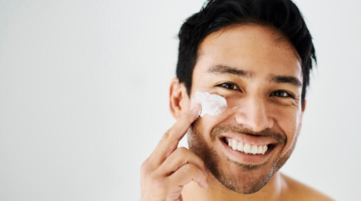 man putting lotion on face